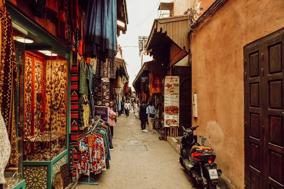 Narrow souk alley in the Marrakech medina lined with craft shops and shoppers