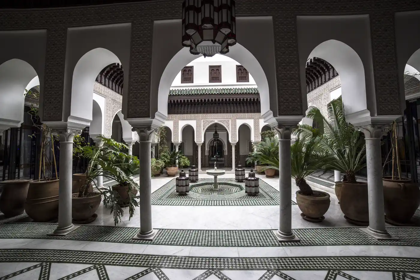 Riad courtyard in Marrakech with zellige tilework, carved arcades and a central fountain &mdash; an exclusive-use event venue contracted directly by our DMC Marrakech desk