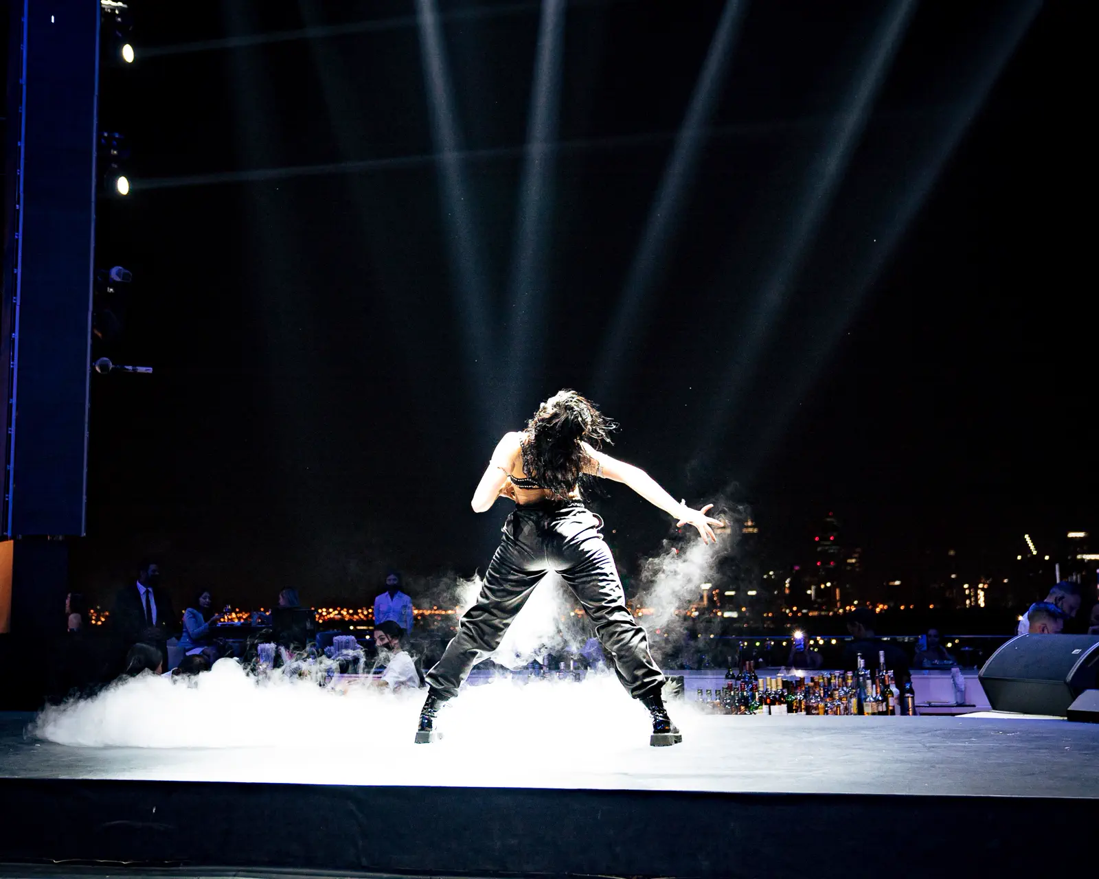 Performer lit by beam lighting and haze on an open-air stage at an evening corporate event