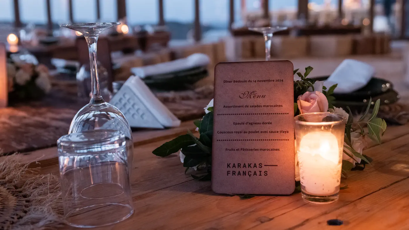 Candlelit dinner table set in a desert camp with a printed menu card for an incentive group